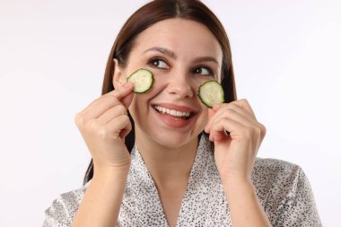 Beyaz arka planda salatalık dilimleri olan bir kadın.