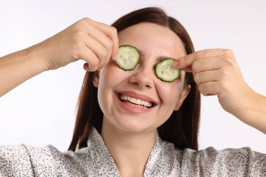 Beyaz arka planda salatalık dilimleri olan bir kadın.