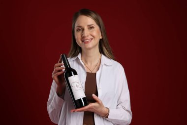 Kırmızı arka planda şarap şişesi olan profesyonel şarap garsonu.