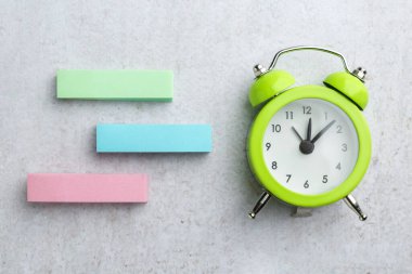 Gri desenli masa üzerinde boş notlar ve alarm saati, düz yatıyordu