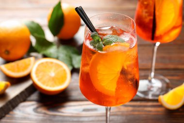 Bardaklar ferahlatıcı spritzer kokteyli ve portakallar ahşap masada, yakın plan.