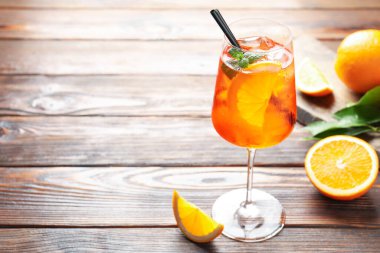Bir bardak serinletici spritzer kokteyli ve portakallar ahşap masada. Metin için boşluk