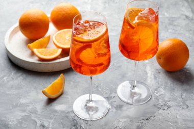 Gri desenli masaya serinletici spritzer kokteyli ve portakallar.