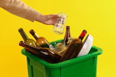 Turuncu arka plandaki çöp kutusuna çöp atan kadın, yakın plan. Atık sıralama