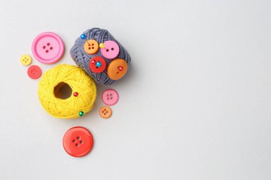 Beyaz arka planda iğne ve düğmeleri olan iplik yumakları, düz bir zemin. Metin için boşluk