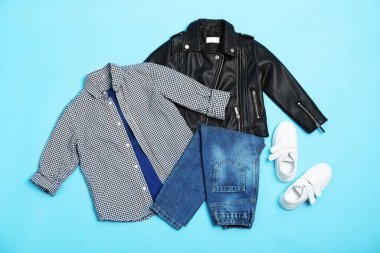 Açık mavi arka planda şık çocuk kıyafetleri ve ayakkabıları olan düz bir kompozisyon.