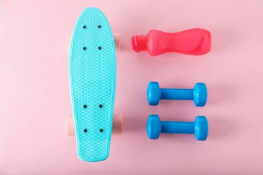 Parlak bir pano, bir şişe içki ve pembe arka planda halterler, düz uzanma.