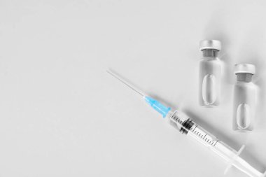 Gri arka planda aşı ve şırınga, düz yerde. Metin için boşluk