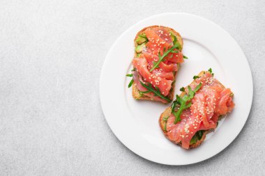 Somon, roka ve avokado ile nefis bruschetalar açık gri masa, üst manzara. Metin için boşluk