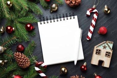 Yeni yıl hedefleri. Planlayıcı, kalem ve Noel dekoru siyah masada, düz yatıyordu