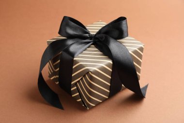 Kahverengi arka planda güzel paketlenmiş hediye, yakın plan.