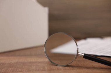 Büyüteç ve belgeler ahşap masada, yakın plan.