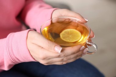Bir fincan limonlu çay tutan kadın, yakın plan.