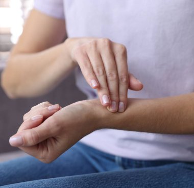 Kadın nabzını evde kontrol ediyor, yakın plan.