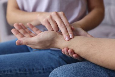 Kadın adamın nabzını kontrol ediyor. Parmakları evde, yakın plan.