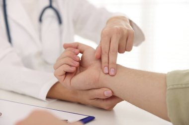 Doktor masadaki parmaklarıyla adamın nabzını kontrol ediyor.