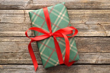 Kağıda sarılı güzel bir hediye kutusu, ahşap masa üzerinde kareli desenli, üst görünüm.