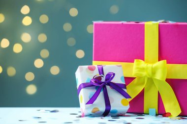 Noel hediyesi kutuları ve beyaz masanın üzerindeki konfeti arka planda bulanık ışıklarla, yakın plan. Metin için boşluk