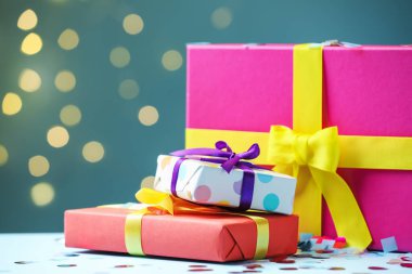 Birçok Noel hediyesi kutusu ve konfeti beyaz masada arka planda bulanık ışıklarla, yakın plan