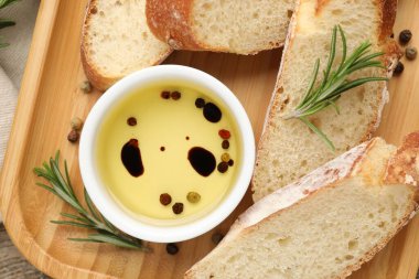 Ekmek dilimleri zeytinyağı, biberiye ve baharatlar ahşap masada, düz yerde.