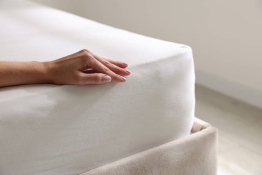 Yatakta yumuşak yatağa dokunan kadın, yakın plan.