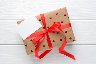 Beyaz ahşap masa üzerinde boş bir kartın olduğu güzel bir hediye kutusu.