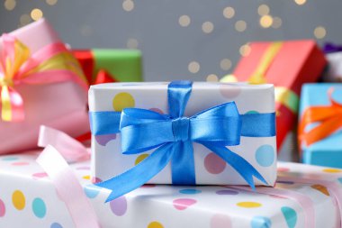 Gri arka planda güzel paketlenmiş hediyeler, bulanık ışıklar, yakın plan. Bokeh etkisi