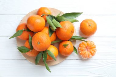 Taze mandalina ve yeşil yapraklar beyaz ahşap masada, düz yatıyordu.