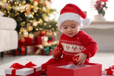 Noel Baba şapkalı şirin bir bebek, evde takılar ve hediyeler. Noel sezonu