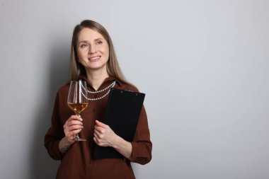 Açık gri arka planda beyaz şarap ve panosu olan profesyonel bir şarap garsonu. Metin için boşluk