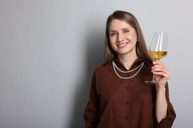 Açık gri arka planda beyaz şarap kadehi olan profesyonel bir şarap garsonu. Metin için boşluk