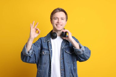 Kulaklıklı yakışıklı genç adam sarı arka planda iyi bir hareket gösteriyor.