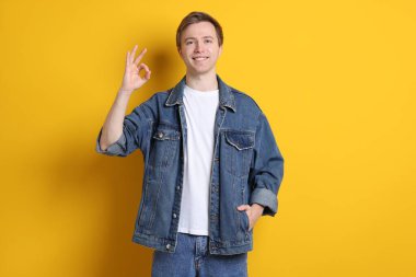 Yakışıklı genç adam sarı arka planda iyi bir hareket gösteriyor.