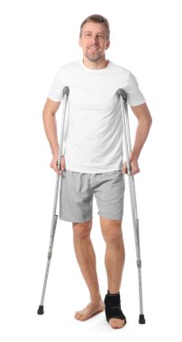 Beyaz arka planda yaralı bacağı ve koltuk değneği olan bir adam.