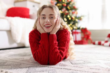 Evdeki bulanık ışıklara karşı süveter giymiş gülümseyen kadın portresi. Mutlu Noeller ve mutlu yıllar.