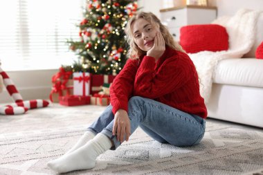 Evdeki bulanık ışıklara karşı süveterli güzel bir kadın. Mutlu Noeller ve mutlu yıllar.