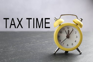 Vergi zamanı. Gri masada sarı alarm saati