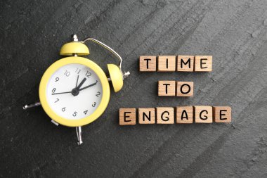 Harekete geçme zamanı. Çalar saat ve tahta küpler koyu gri taş masa, düz yatıyordu.