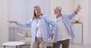 Mutlu yaşlı çift evde dans ediyor.