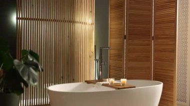 Küvet, ahşap perde ve banyoda yeşil ev bitkisi, kamera geliyor. İç tasarım