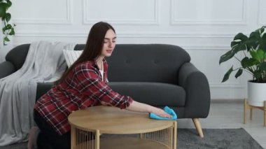 İçerideki ahşap masadan tozları silen kadın