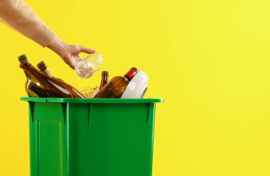 Turuncu arka planda çöp kutusuna çöp atan bir kadın. Mesaj için yer var. Atık sıralama