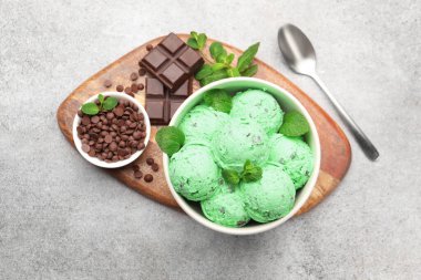 Yummy mint chocolate chip ice cream served on grey, flat lay
