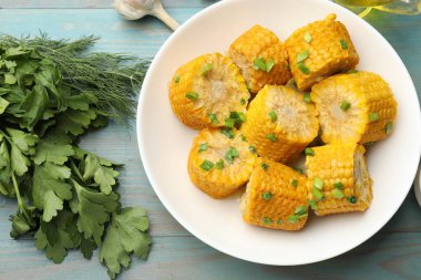 Kaynamış mısır koçanları yeşil soğanlı, maydanozlu ve dereotlu açık mavi ahşap masa, düz yatıyordu.