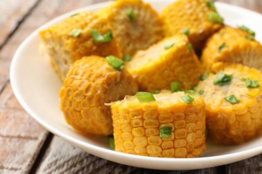 Ahşap masada yeşil soğanlı haşlanmış mısır koçanları, yakın plan.