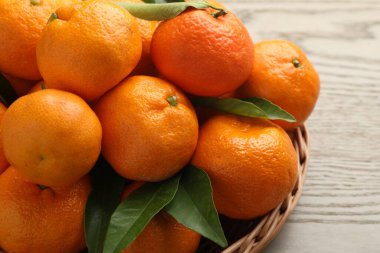 Taze mandalina ve yeşil yapraklar ahşap masada, yakın plan.