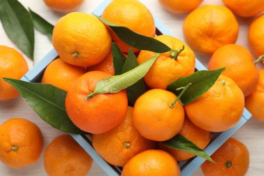 Taze mandalina ve yeşil yapraklar beyaz ahşap masada, düz yatıyordu.