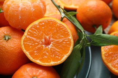 Taze mandalina ve yeşil yapraklar masada, yakın plan.