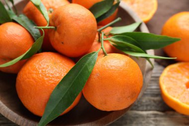 Taze mandalina ve yeşil yapraklar ahşap masada, yakın plan.