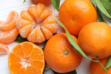 Taze mandalina ve yeşil yapraklar beyaz ahşap masada, düz yatıyordu.